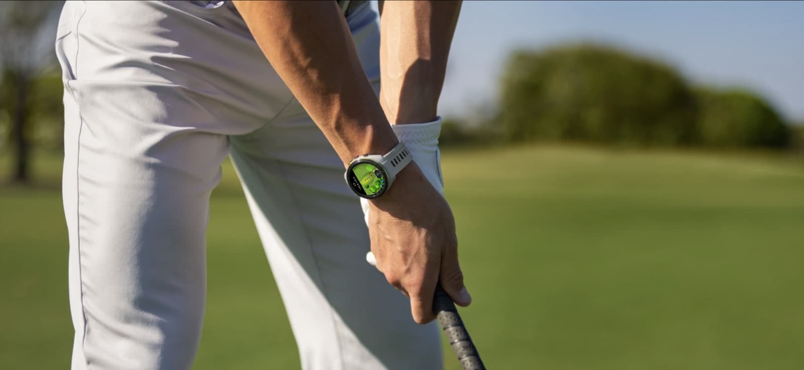 A golfer at address with the watch on their wrist, the green behind them.